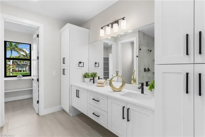 Dual-sink vanity w/ quartz countertops, sleek white cabinetry & contemporary lighting complements the spa-like design.