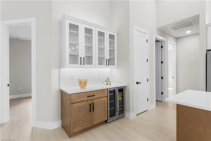 Built-in BUTLER'S PANTRY w/ quartz countertop, glass-front cabinetry, warm wood base cabinets & WINE REFRIGERATOR, ideal for BEVERAGE STATION, COFFEE BAR, or EXTRA STORAGE & PREP SPACE.