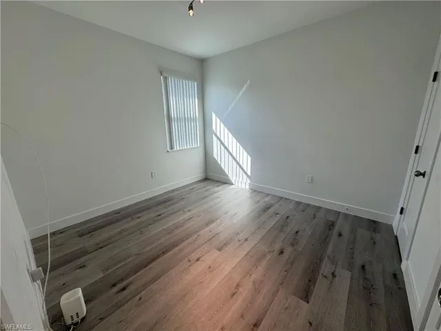 Wood-finish flooring, neutral wall tones, vertical window blinds, and overhead lighting