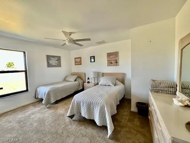 Bedroom with dark colored carpet and a ceiling fan