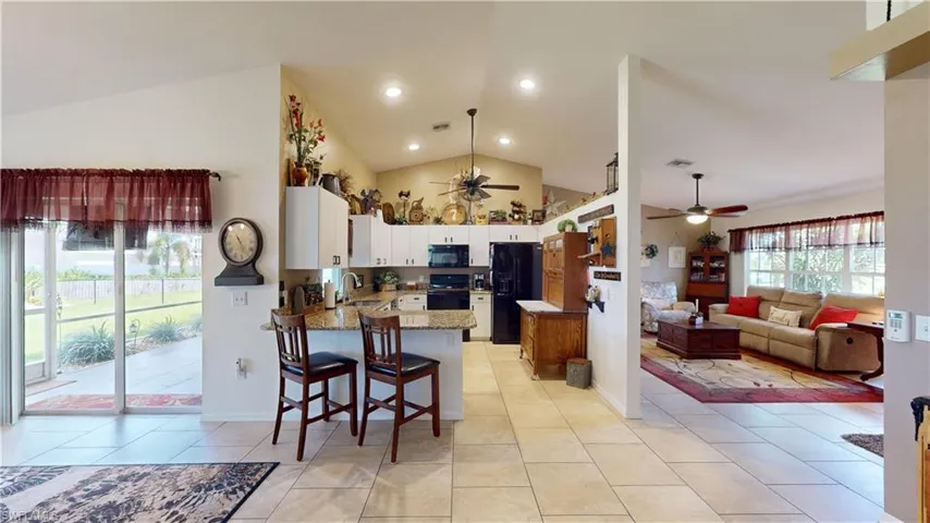 Kitchen featuring white cabinetry, black appliances, kitchen peninsula, ceiling fan, and vaulted ceiling