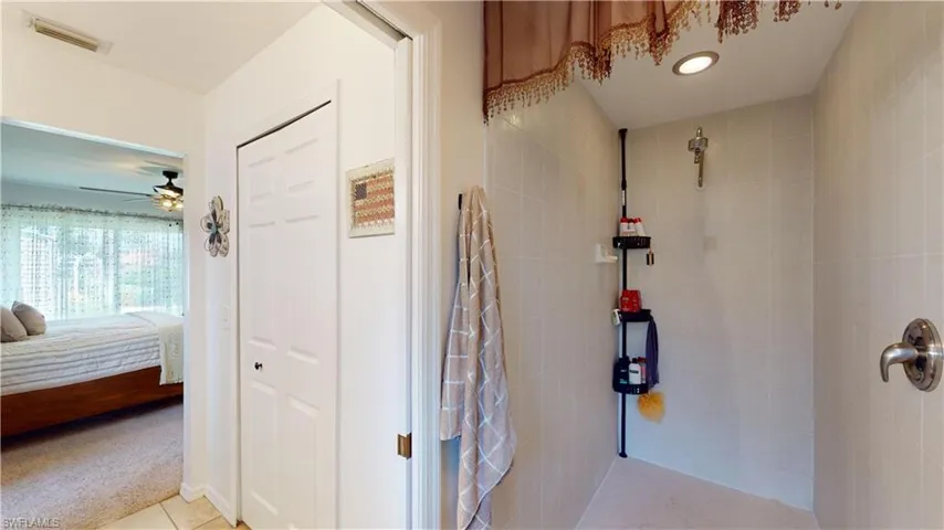 Bathroom featuring a tile shower, ceiling fan, and tile patterned floors