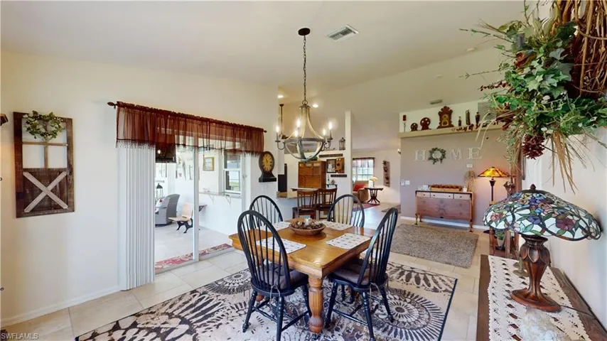 Tiled dining area featuring lofted ceiling and an inviting chandelier