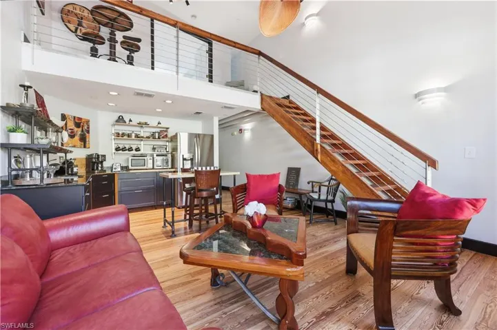 Living area with light wood-type flooring, a towering ceiling, and stairway