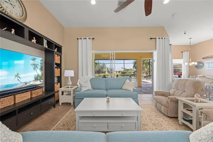 Tiled living room with recessed lighting and ceiling fan with notable chandelier