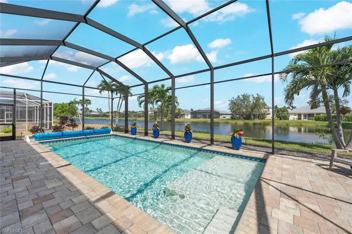 View of pool with a lanai, a covered pool, a water view, paved patio