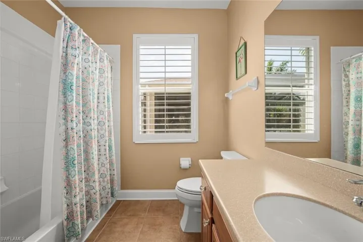 Full bath with vanity, baseboards, shower / tub combo, toilet, and tile patterned flooring