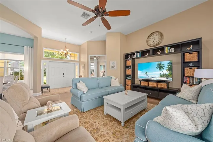 Living room featuring arched walkways, visible vents, high vaulted ceiling, and ceiling fan with notable chandelier