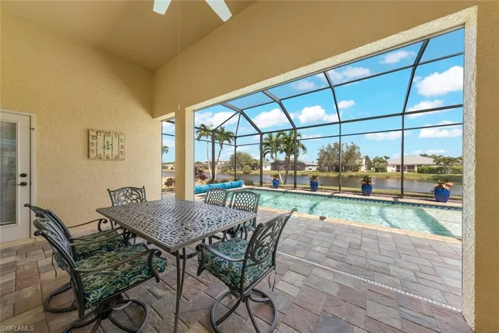 View of patio / terrace with an outdoor pool, outdoor dining space, glass enclosure, and a water view