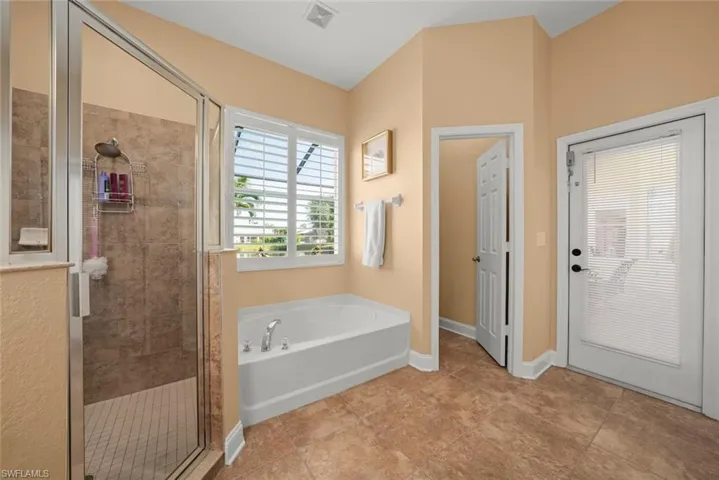 Primary bath featuring baseboards, a garden tub, visible vents, door out to pool from primary bathroom