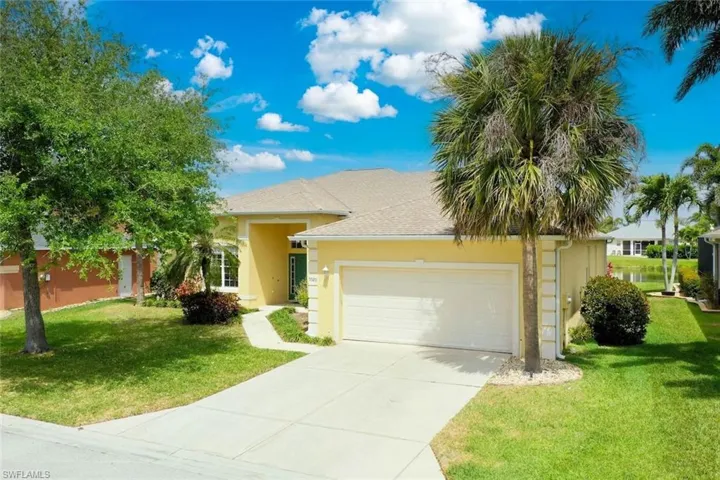 View of front of property with an attached garage, driveway, a front yard, and stucco siding