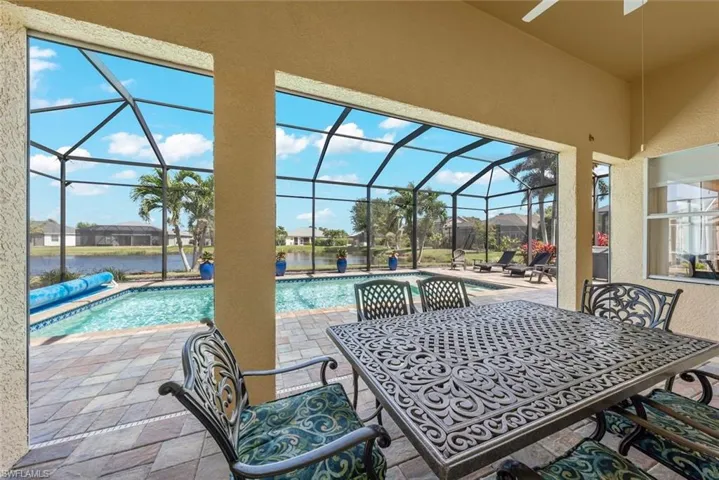 View of patio / terrace featuring an outdoor pool, outdoor dining area, glass enclosure, and a water view