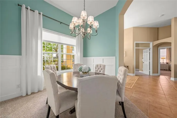 Tiled dining space with arched walkways, a wainscoted wall, and a notable chandelier