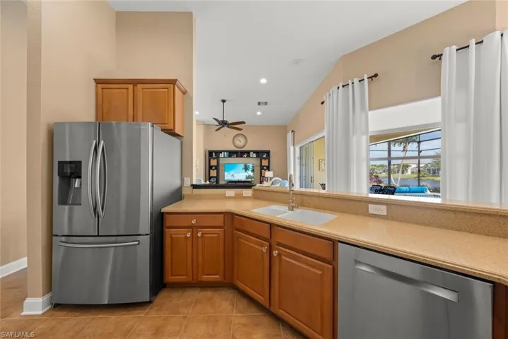 Kitchen with a sink, appliances with stainless steel finishes, ceiling fan, light countertops, and light tile patterned floors