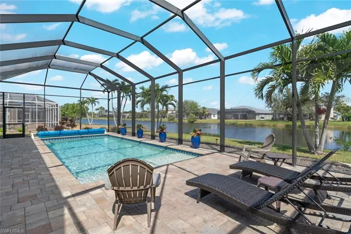 View of pool featuring a patio area, a covered pool, glass enclosure, and a water view
