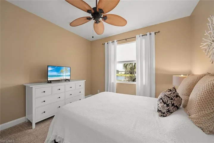 Bedroom with ceiling fan, light carpet, and baseboards