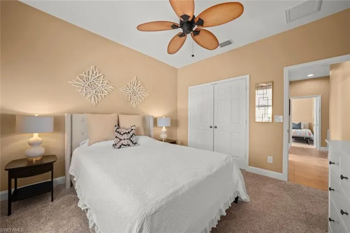 Bedroom featuring light colored carpet, baseboards, visible vents, and a closet