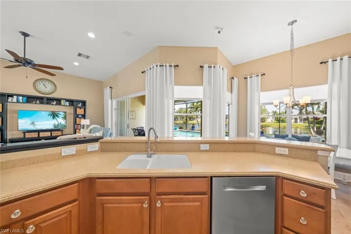 Kitchen with a sink, plenty of natural light, open floor plan, dishwasher, and lofted ceiling