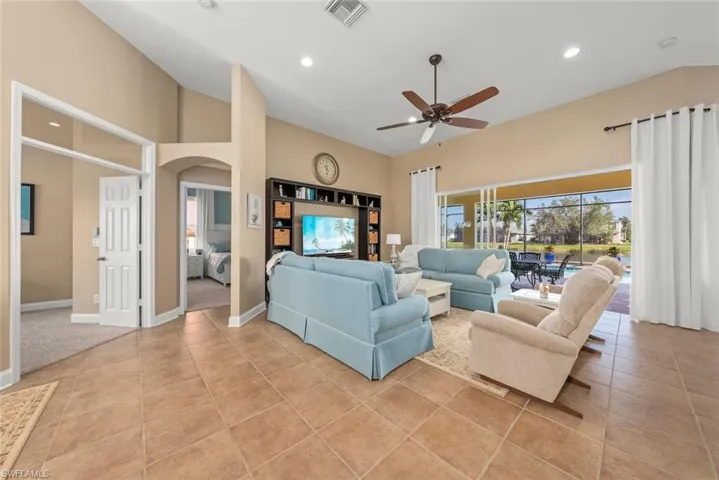 Living area featuring a ceiling fan, light tile patterned flooring, arched walkways, visible vents, and recessed lighting