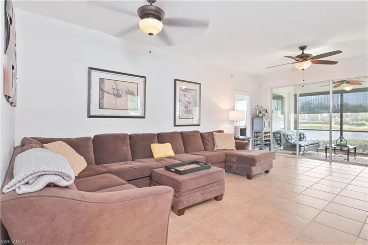 Living room featuring ceiling fan, light tile patterned floors, and a water view