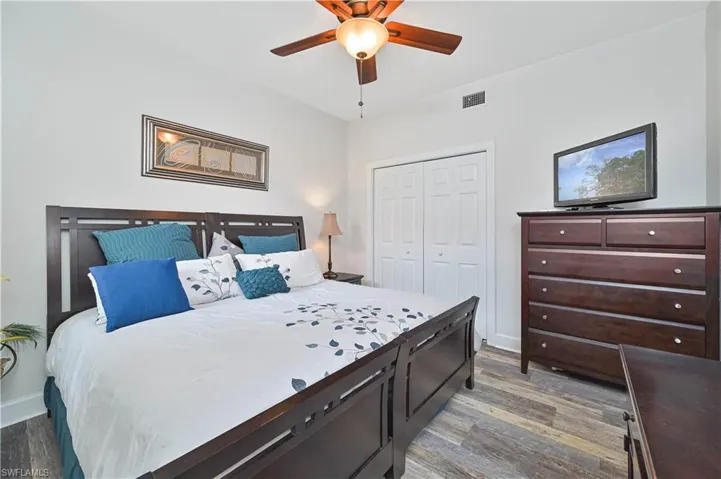 Bedroom with ceiling fan, a closet, and dark wood-style flooring