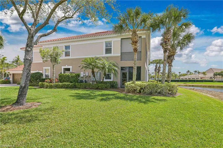 View of front of house featuring a front lawn, stucco siding, a tiled roof, and a water view