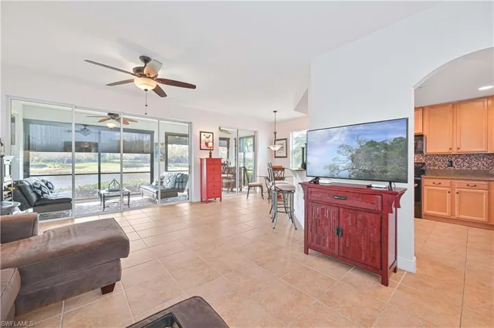 Living area featuring a ceiling fan, arched walkways, and light tile patterned flooring
