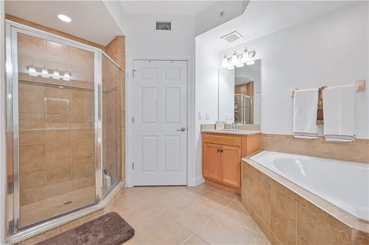 Bathroom featuring vanity, a stall shower, light tile patterned floors, and a bath