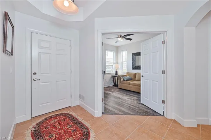Foyer with a ceiling fan, arched walkways, and light tile patterned flooring
