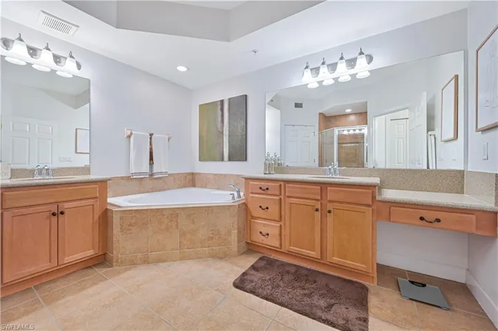 Full bath with a stall shower, two vanities, a bath, and light tile patterned floors