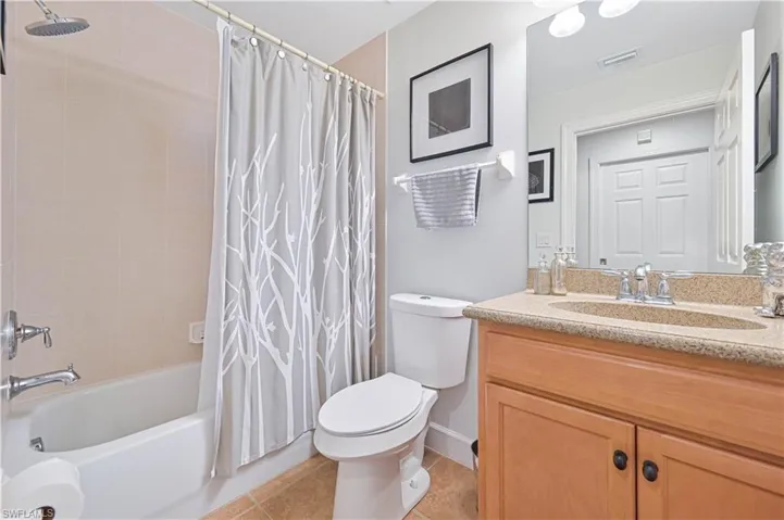 Bathroom featuring vanity, shower / tub combo with curtain, and light tile patterned floors