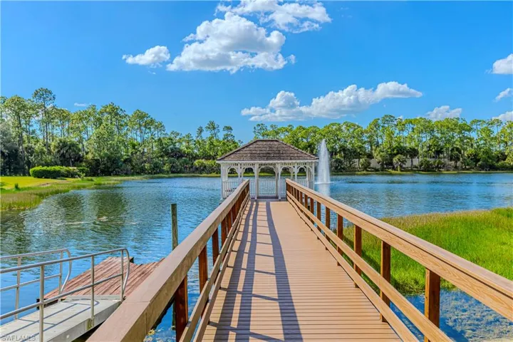 Dock with a water view, a gazebo, and view of wooded area