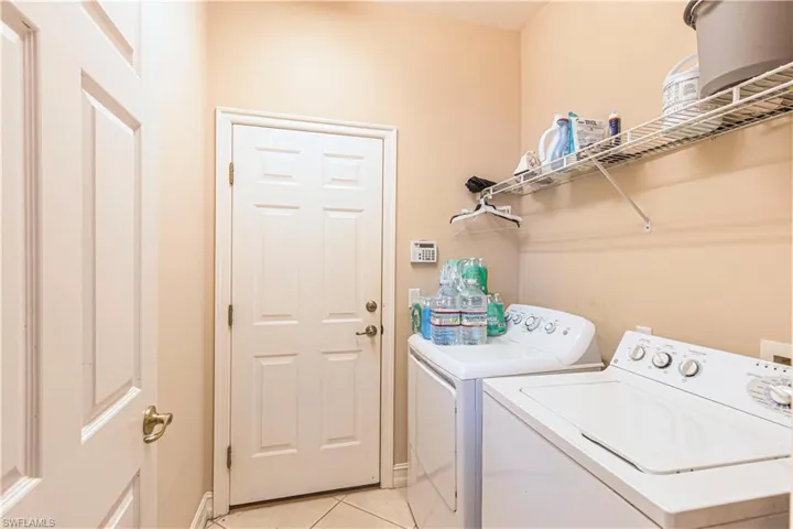 Washroom featuring light tile patterned flooring and washer and clothes dryer