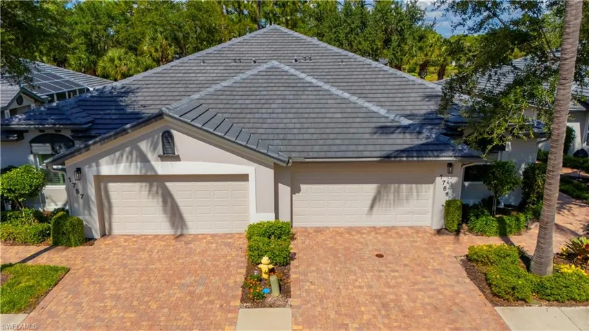 View of front facade featuring decorative driveway, stucco siding, an attached garage, and a tile roof