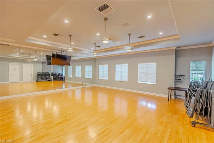 Living area with a tray ceiling, plenty of natural light, light wood-style floors, ornamental molding, and recessed lighting