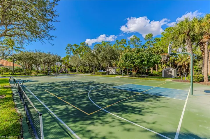 View of basketball court featuring community basketball court, view of scattered trees, and a shed