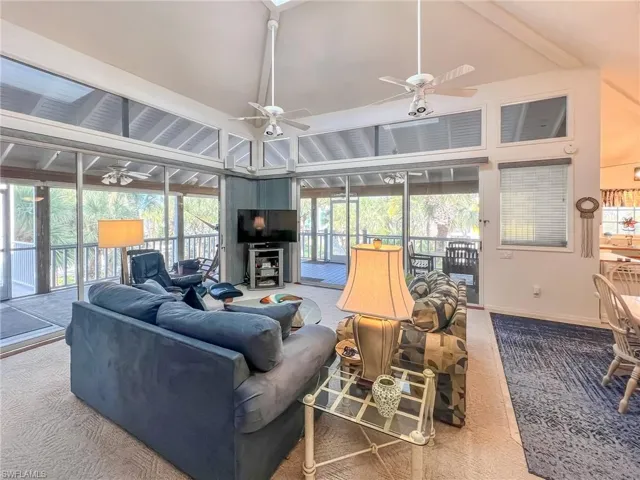Living area featuring carpet floors, high vaulted ceiling, baseboards, and a ceiling fan