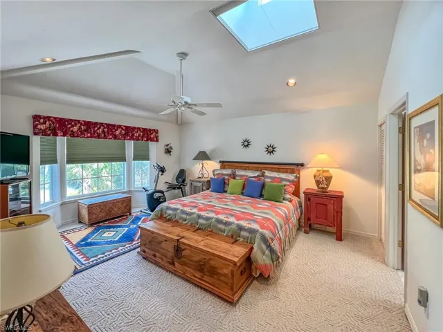 Bedroom featuring vaulted ceiling with skylight, a ceiling fan, carpet flooring, and recessed lighting