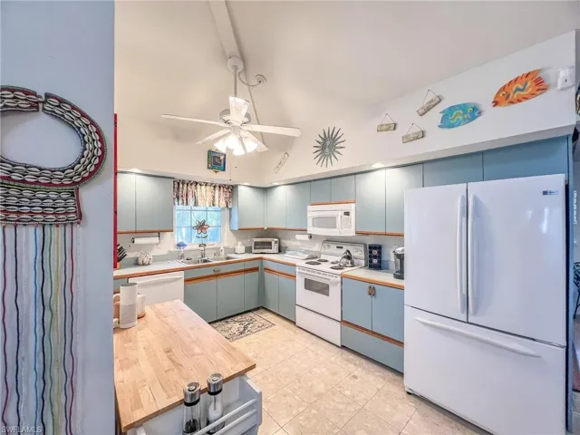 Kitchen with a toaster, light countertops, a ceiling fan, a sink, and white appliances
