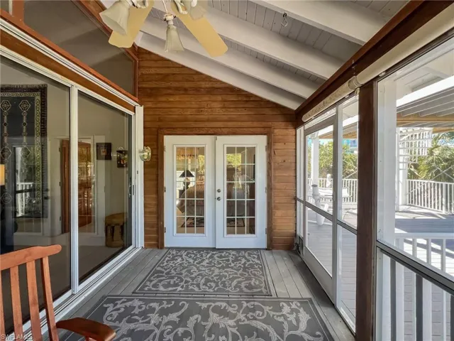 Unfurnished sunroom featuring a ceiling fan, french doors, and lofted ceiling with beams