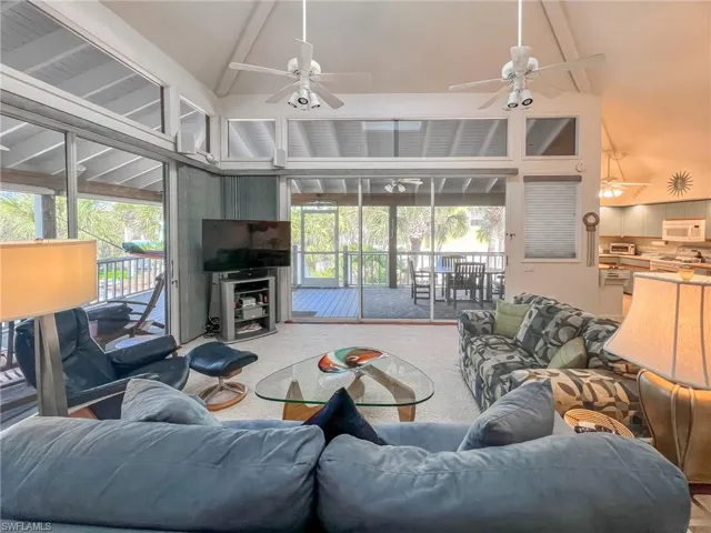 Living room featuring carpet floors, ceiling fan, high vaulted ceiling, and beamed ceiling