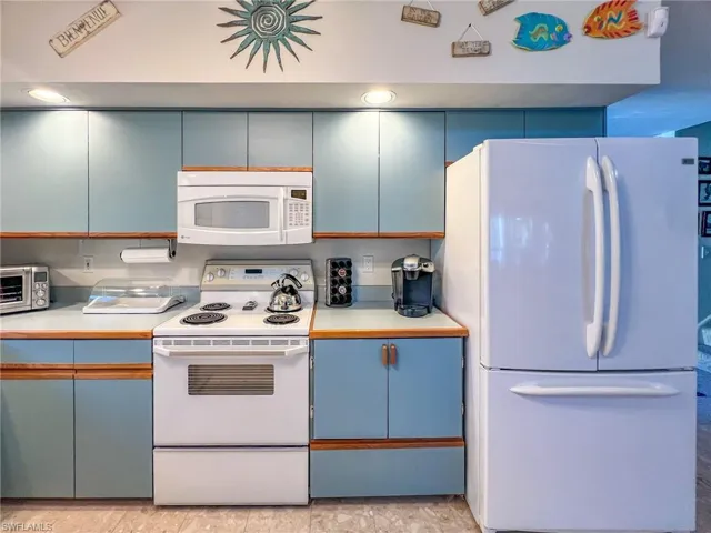 Kitchen with light countertops, white appliances, visible vents, and blue cabinets