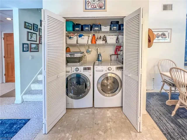 Clothes washing area with laundry area, independent washer and dryer, visible vents, and baseboards