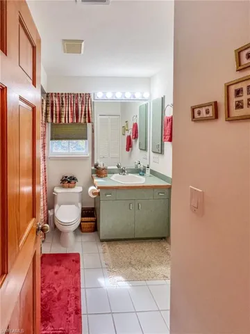 Bathroom featuring toilet, tile patterned floors, visible vents, and vanity