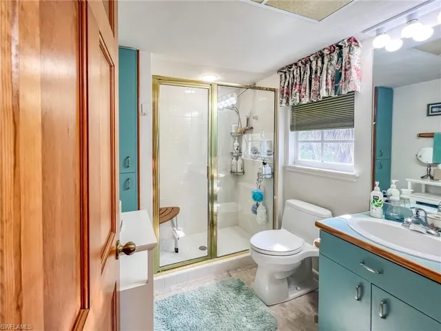 Bathroom featuring toilet, a stall shower, tile patterned floors, and vanity