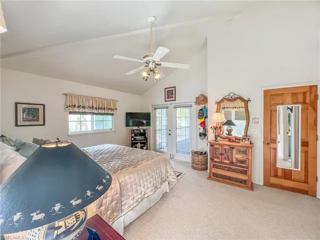 Carpeted bedroom featuring access to outside, high vaulted ceiling, a ceiling fan, and french doors