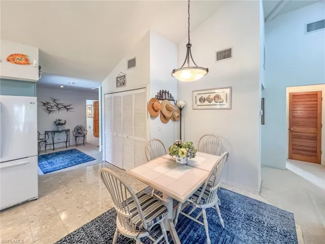 Dining room featuring high vaulted ceiling, baseboards, and visible vents