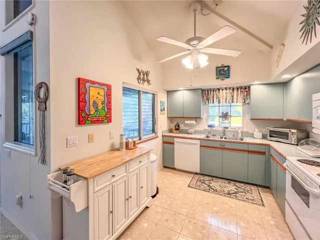 Kitchen featuring light countertops, white appliances, a healthy amount of sunlight, and a sink