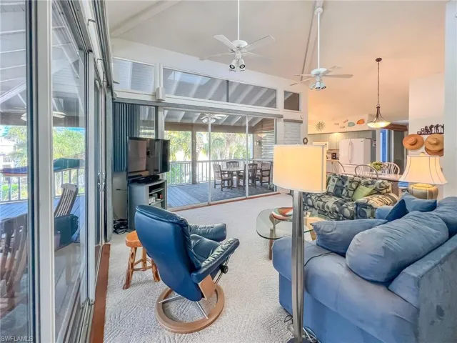 Carpeted living area featuring ceiling fan and high vaulted ceiling