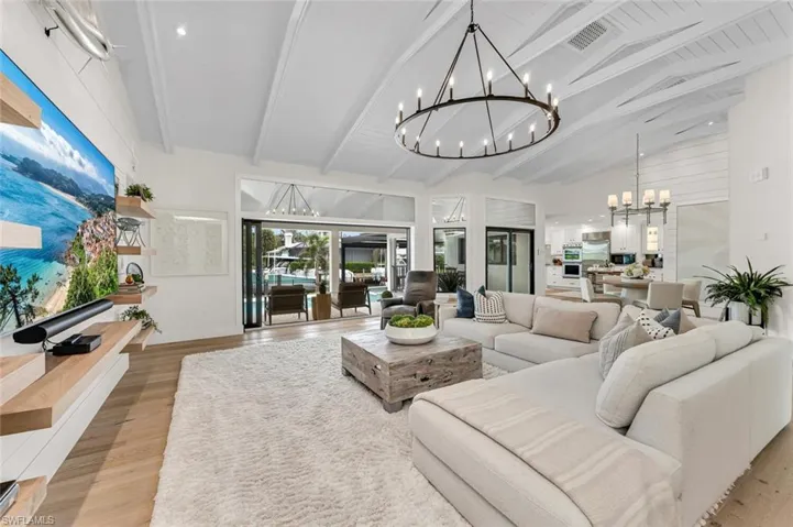 Living area featuring visible vents, an inviting chandelier, light wood-style floors, high vaulted ceiling, and beamed ceiling